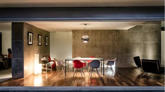 sala com mesa com 6 cadeiras, espaço amplo, parede de concreto aparente