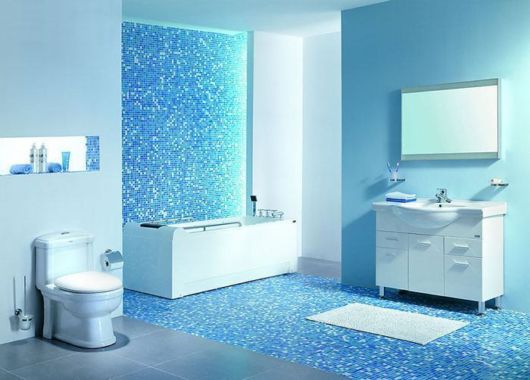 banheiro com louças brancas e faixa de pastilhas de cor azul claro e branco montada na vertical
