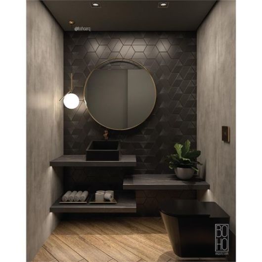 banheiro com louças pretas, paredes de cimento queimado e faixa de azulejos pretos na parede da pia, com espelo grande e redondo