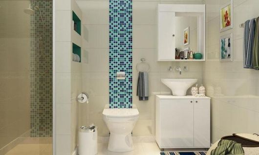 banheiro com louças brancas e faixa de pastilhas disposta na vertical em vários tons de azul