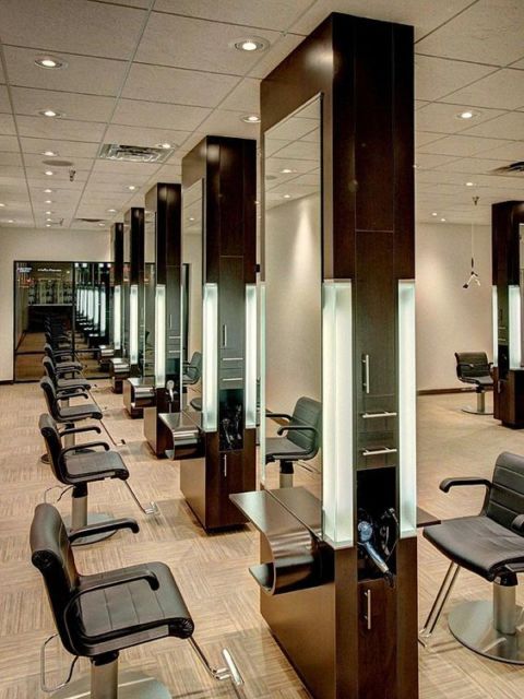 Salão de beleza com grandes espelhos embutidos em molde de madeira e iluminação de LED