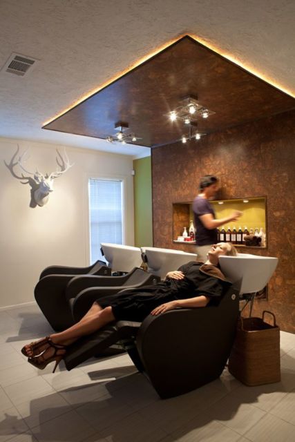 cadeiras de lavar o cabelo com descanso para pés em tom marrom, paredes brancas e teto parcialmente rebaixado de madeira