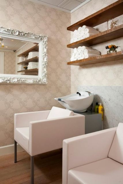 área de salão de beleza para lavar cabelos com armário no alto com toalhas brancas em rolos, cadeiras e louça branca