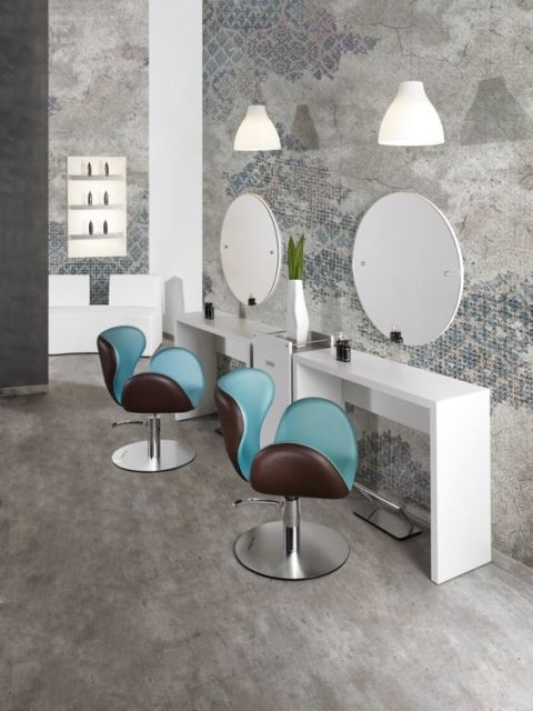 salão de beleza com cadeiras em azul turquesa e marrom, paredes cinza e espelhos redondos