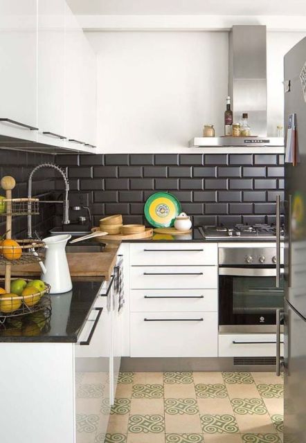 cozinha com armários brancos, fogão, coifa e geladeira cromados e faixa horizontal de tijolinhos pretos