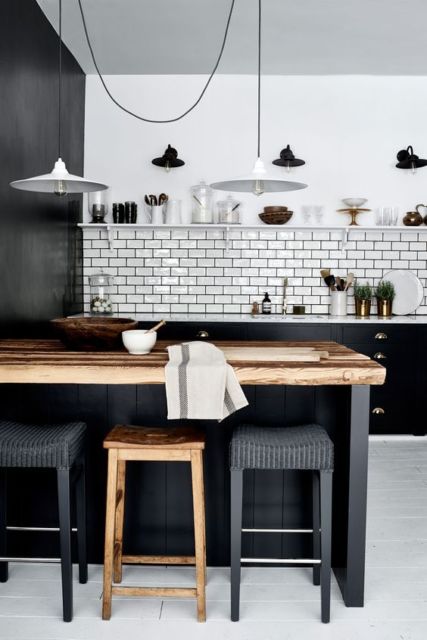Cozinha americana com balcão em madeira de demolição, parede branca com faixa de tijolinhos ao fundo e parede preta 