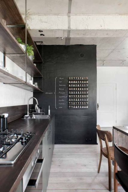 cozinha com parede de lousa e teto de concreto com tubulações de ferro aparentes