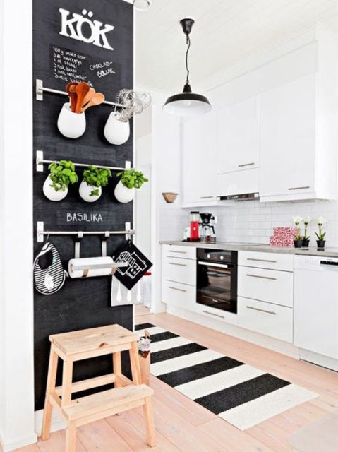 cozinha com armários brancos, parede preta de lousa e forno preto ambutido