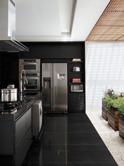 cozinha com eletrodomésticos cromados embutidos na parede preta e teto branco