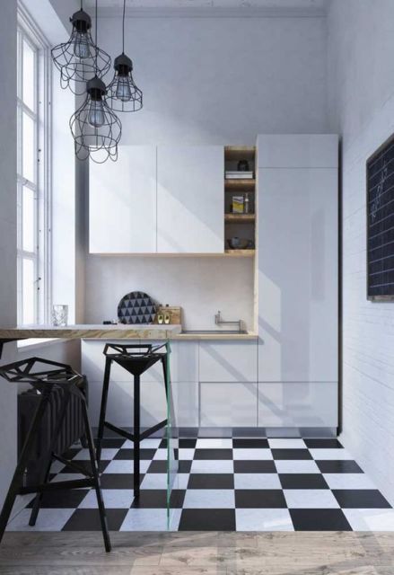 Pequena cozinha com armário branco, piso xadrez e pequeno balcão de madeira