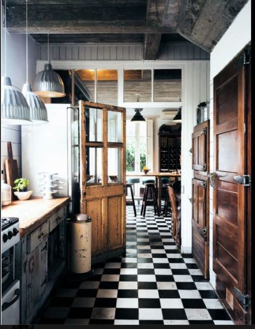 cozinha com piso xadrez, armários de madeira, teto de concreto e lustres em tom de alumínio