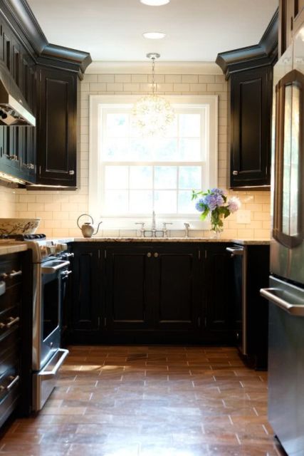 cozinha com armários pretos e paredes e teto brancos, piso de azulejo amarronzado