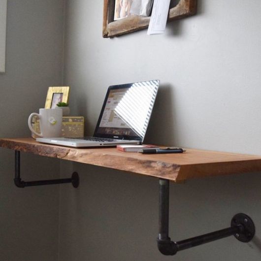 mesa de madeira de demolição chumbada na parede, laptop, caneca sobre a mesa, paredes cinza
