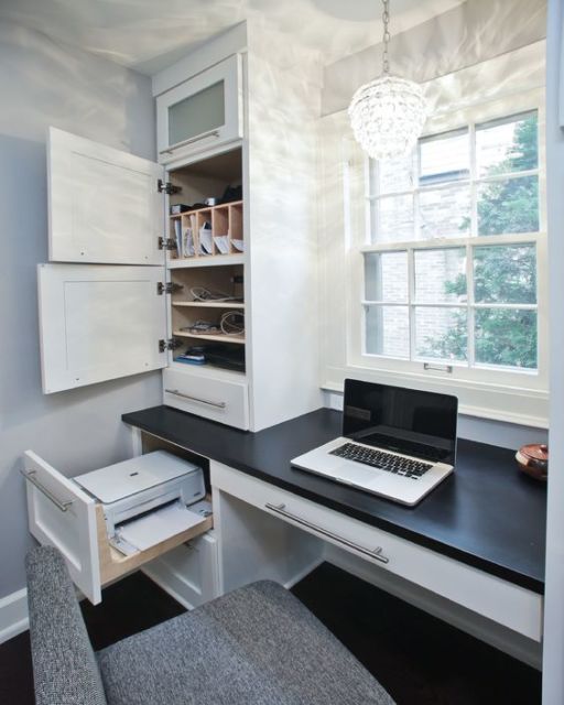 bancada de madeira preta integrada com gavetas e estante brancas, cadeira cinza mesclado e notebook branco. Janela sobre a bancada