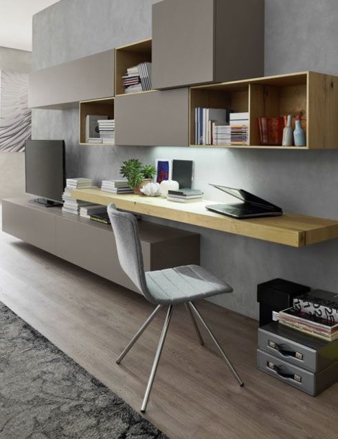 sala de estar com televisão , armários em tom de cinza suspensos, mesa chumbada na parede de madeira, cadeira cinza claro e piso de madeira em tom claro