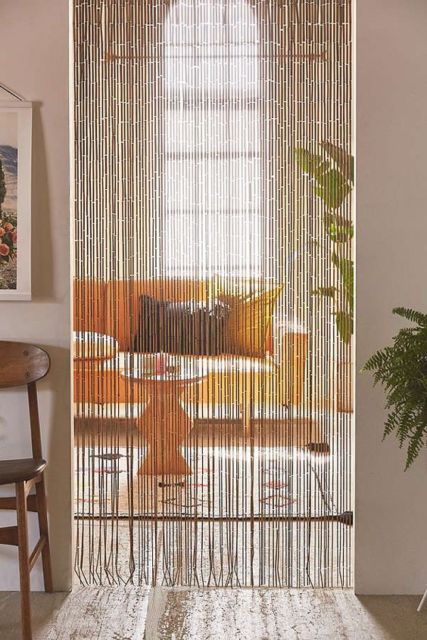 cômodos separados por uma cortina de bambu com janela ao fundo