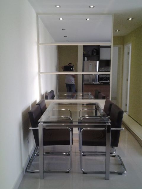 sala de jantar com mesa de vidro e quatro cadeiras marrons e parede toda recoberta de vidro