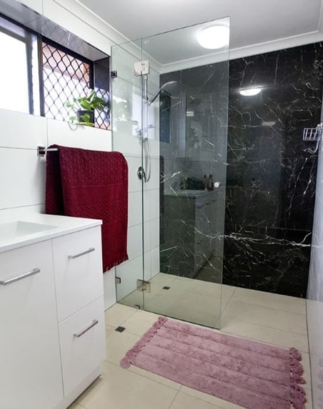 banheiro com parede revestida de mármore preto
