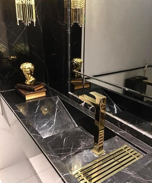 banheiro moderna com cuba esculpida de mármore e torneira dourada