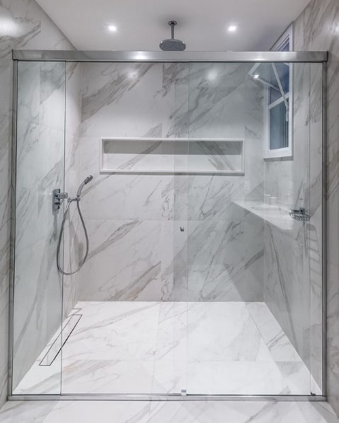 banheiro com revestimento que imita marmore e chuveiro de teto cromado