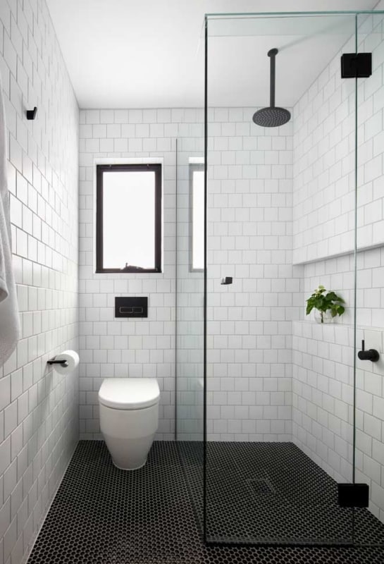 banheiro preto e branco com chuveiro de teto em metal preto