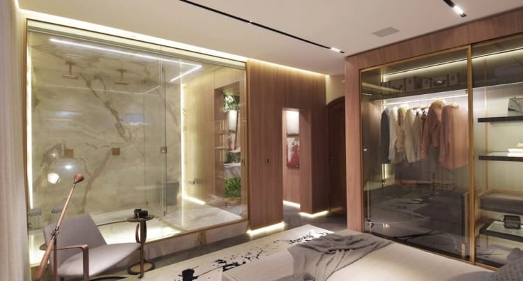 quarto moderno com closet de vidro e banheiro integrado