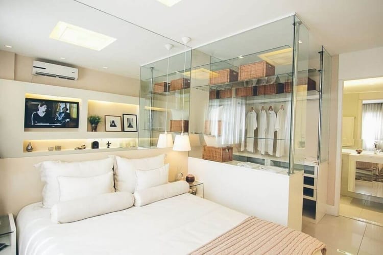 quarto de casal moderno com closet de vidro e banheiro