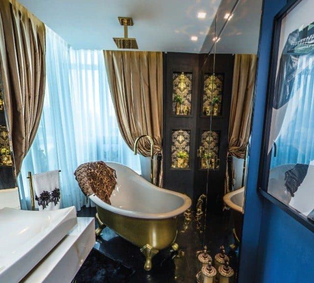 banheiro de luxo com banheira dourada e chuveiro de teto