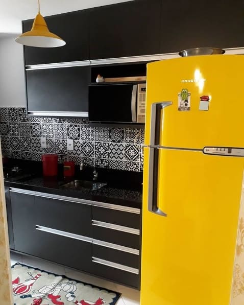 cozinha preta com geladeira amarela