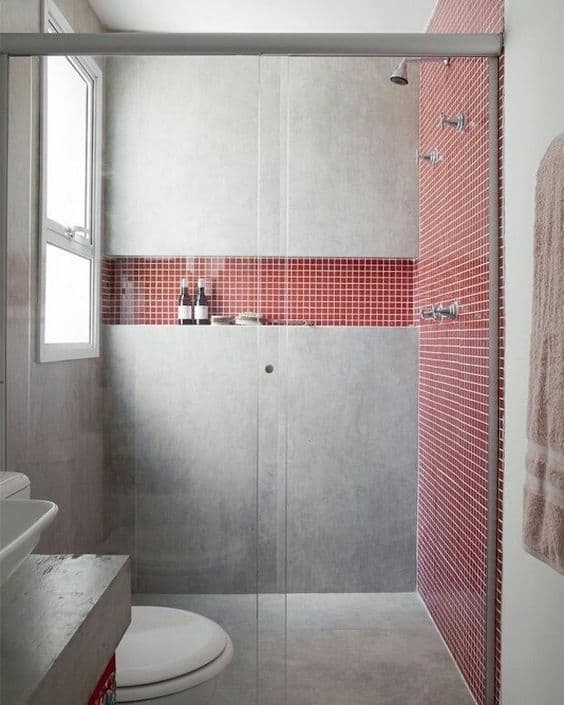 banheiro com pastilhas vermelhas e parede de cimento queimado