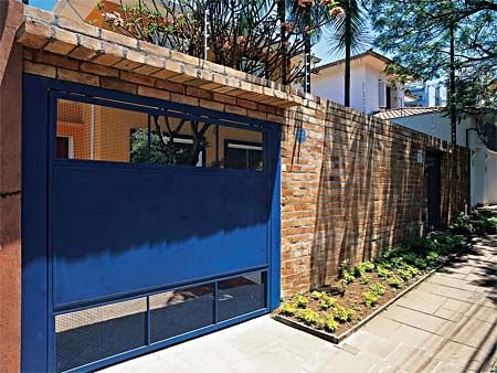 casa com muro de tijolinhos e portao basculante azul