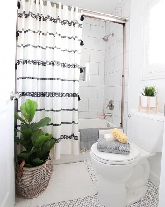 banheiro pequeno com banheira e cortina em branco e preto