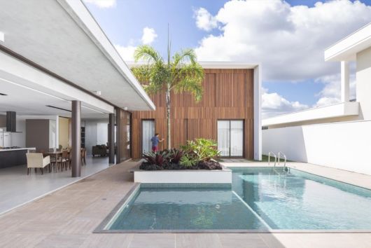 Casas com piscina: modelo em l com parede de madeira