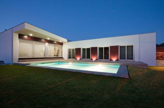 Casas com piscina: casa em l com luzes vermelhas