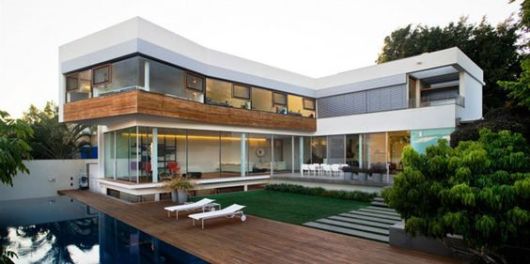 Casas com piscina: casa em l decorada com vidros e madeira