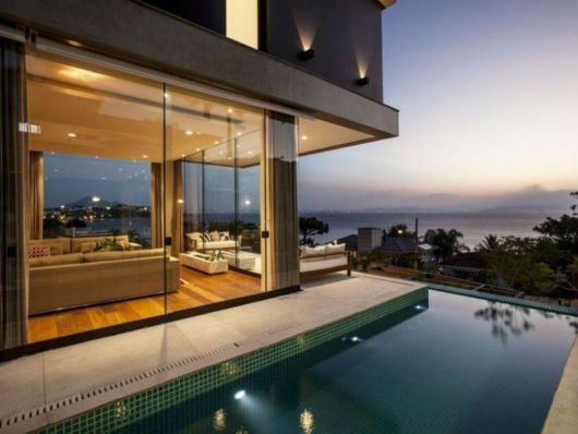 casa grande de vidro com piscina.