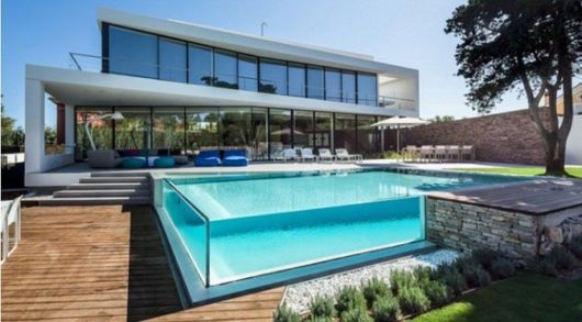 casa de dois anadres de vidro com piscina de vidro.