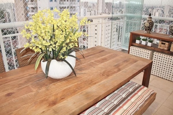 Varanda de apê decorada com mesa grande de madeira