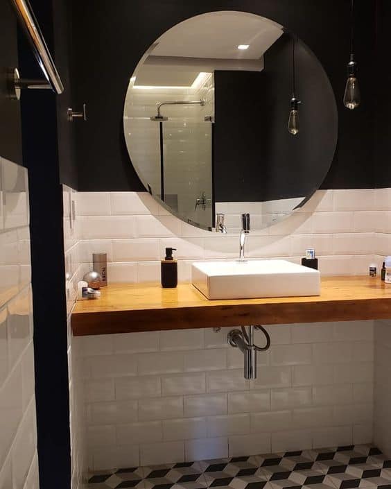 banheiro com parede preta e espelho redondo bisotado